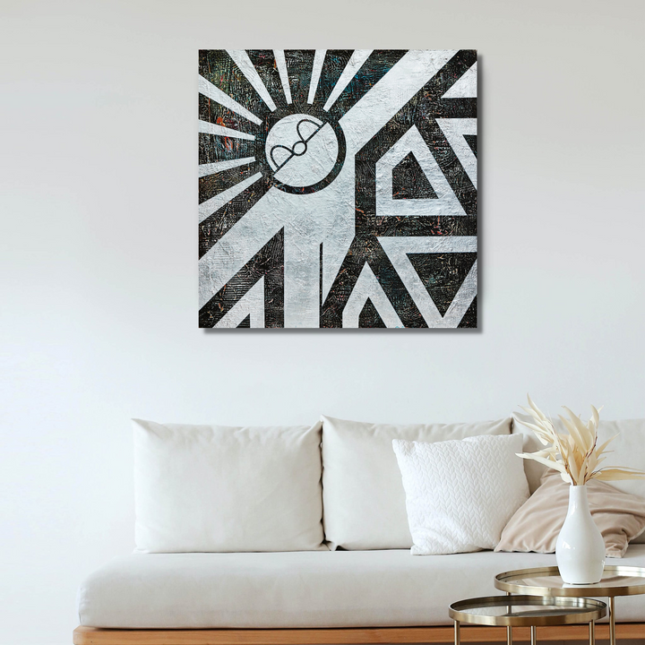 The artwork 'HOPE SPRINGS ETERNAL' by Yusuke Ochiai features striking geometric patterns in black and white, with radiating sunburst lines emerging from a central circular motif. Abstract triangular shapes create a bold, modern composition. Silver leaf accents add metallic highlights against the acrylic on wood, creating a dynamic 34x34 inch contemporary piece.