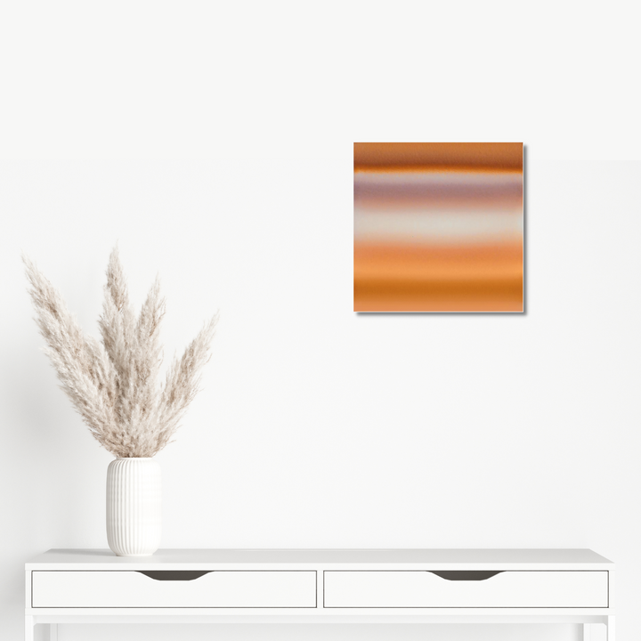 The artwork 'Horizon No. 3' by Daniel Kersh features a square metallic print with smooth gradient transitions from rich copper to warm amber tones. The minimalist composition creates an ethereal atmospheric effect, printed on lustrous Kodak Metallic C-print medium, measuring 15.8 x 15.8 inches.