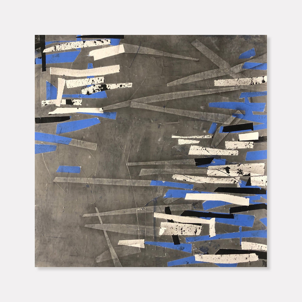 The artwork 'Graphite Ovelook' by Shira Toren features dynamic abstract composition with intersecting geometric shapes in graphite gray, contrasting white textured elements, and vibrant cobalt blue accents. The 24x24 inch print showcases a modern minimalist style with scattered angular forms creating movement across a moody charcoal background.