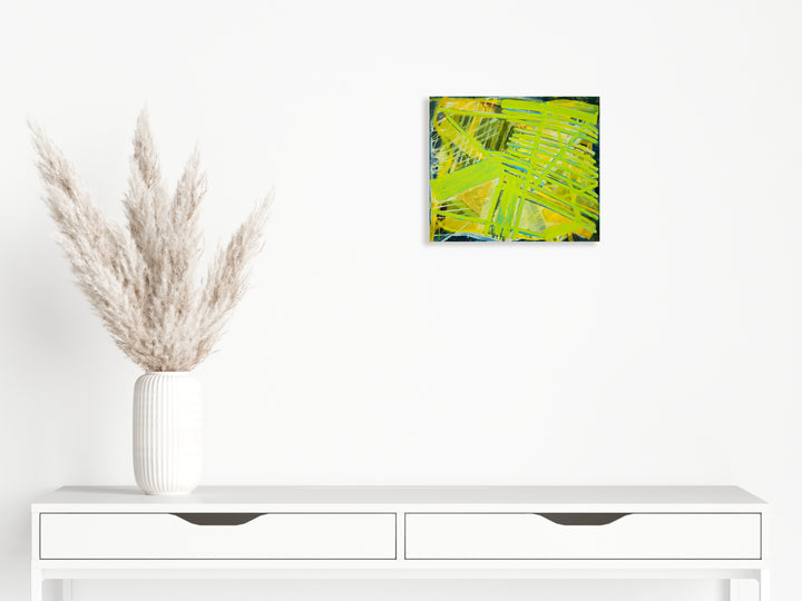 The artwork 'Slide' by Julie Shapiro features vibrant chartreuse and yellow brushstrokes creating dynamic diagonal patterns across the canvas. Bold, gestural marks in lime green intersect with darker olive accents, suggesting movement and energy. The oil painting's textured surface captures abstract expressionist techniques on an 18x21 inch canvas. By Julie Shapiro.