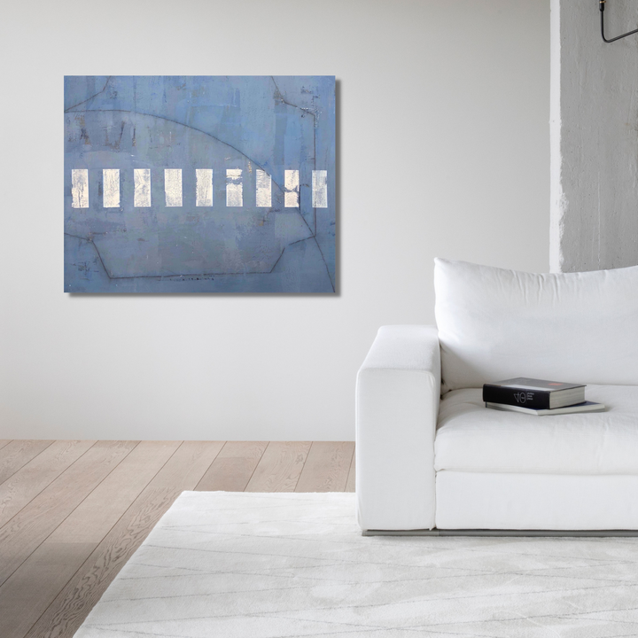 The artwork 'The Edge of Water' by Shira Toren features a minimalist composition with eight white rectangular panels arranged horizontally across a misty blue background. The Venetian plaster texture creates subtle variations in the surface, while delicate curved lines suggest movement through the atmospheric blue canvas, measuring 30x36 inches.